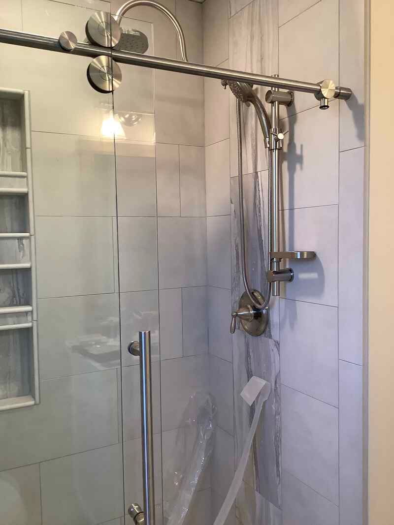 A bathroom with a sliding glass shower door and a shower head.