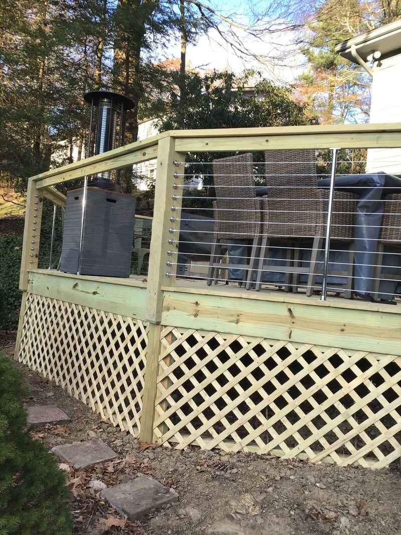 A wooden deck with a lattice fence and stainless steel railing.