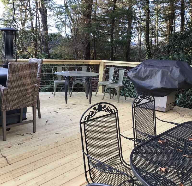 A wooden deck with a table and chairs and a grill