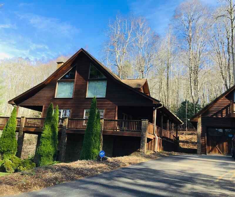 A large log cabin is sitting on top of a hill in the middle of a forest.