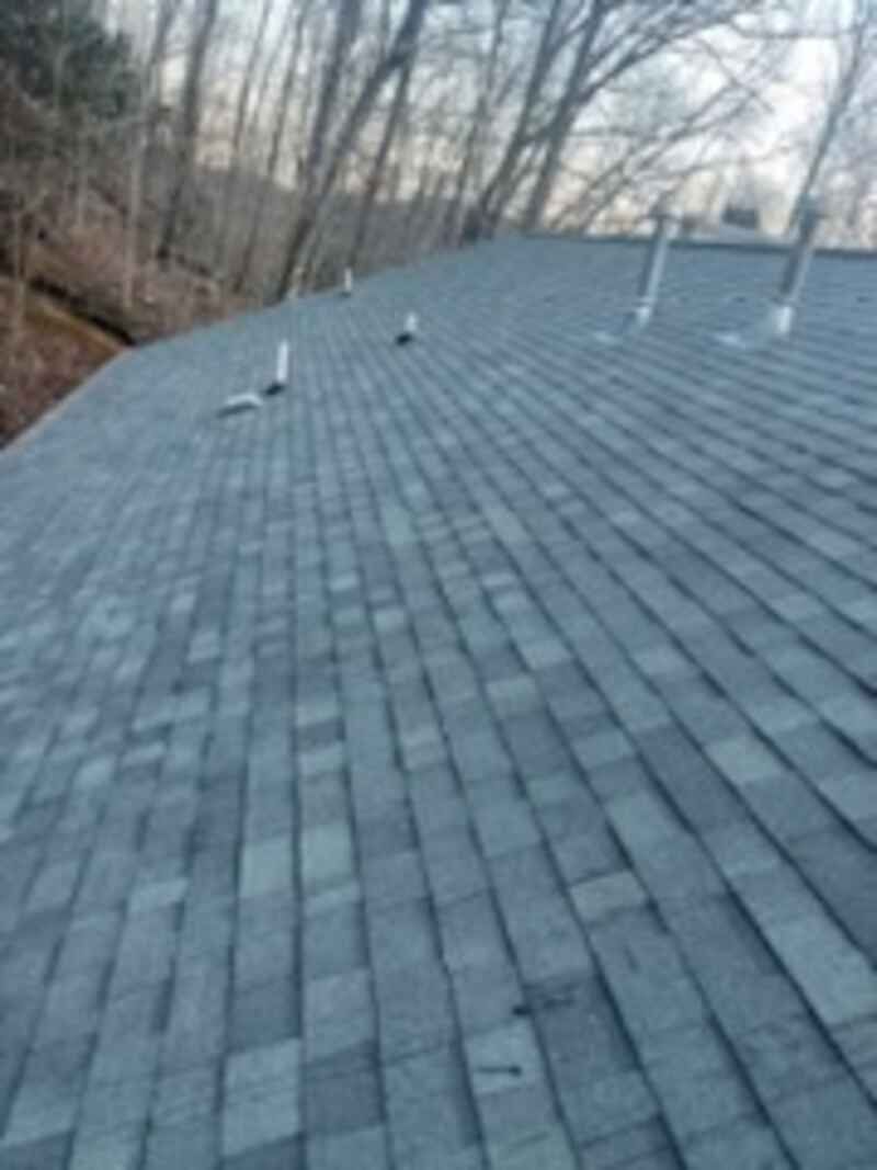 A close up of a roof with a few trees in the background.