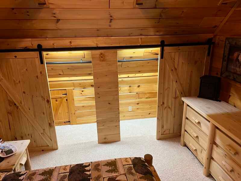 A bedroom in a log cabin with sliding barn doors and a bed.