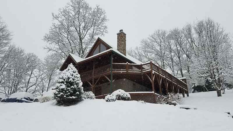 A log cabin covered in snow with trees in the background