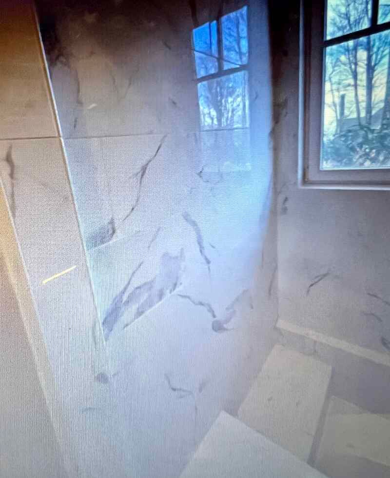 A bathroom with a marble wall and a window.