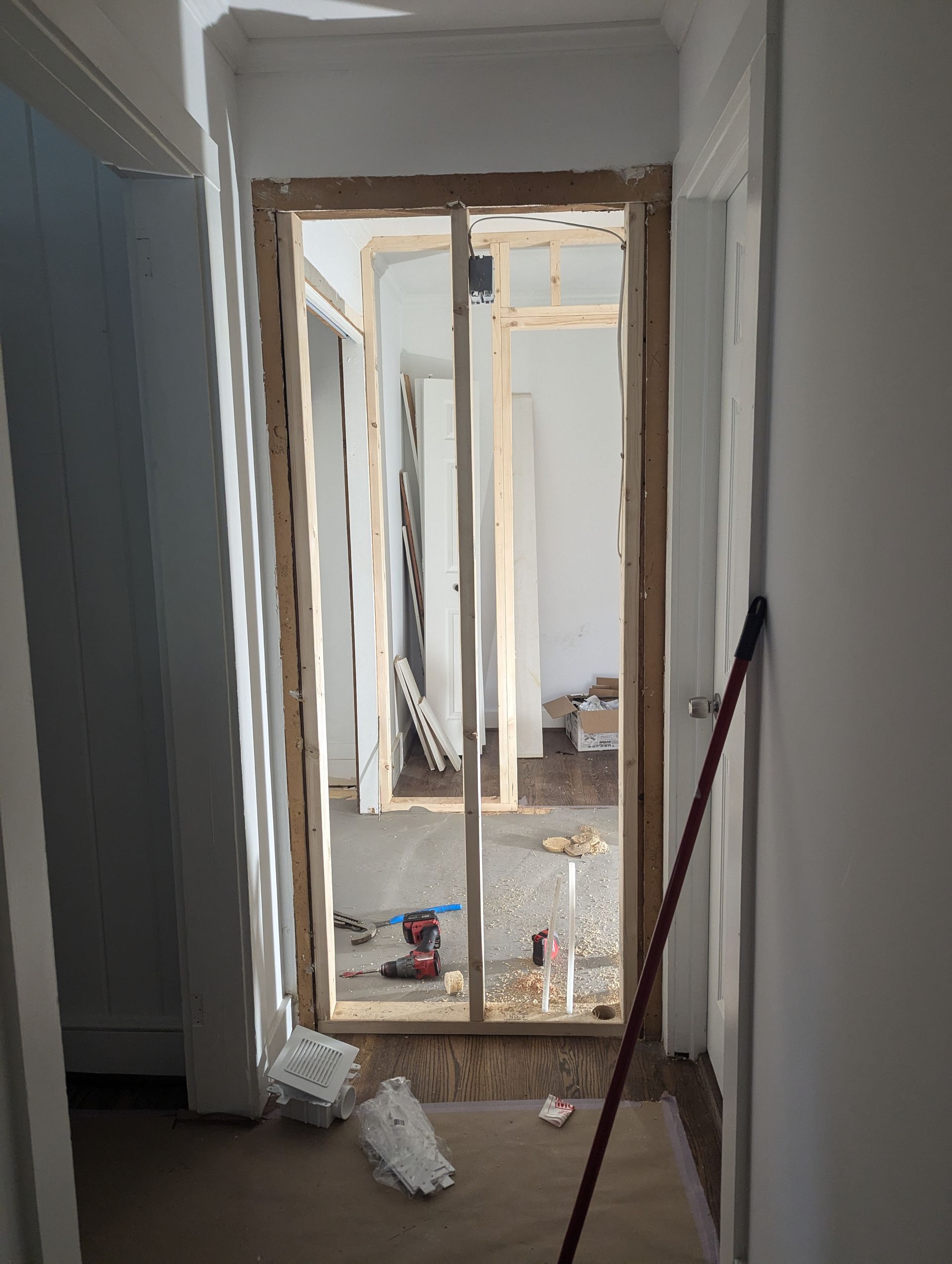 A door is being built in a room with a mop on the floor.