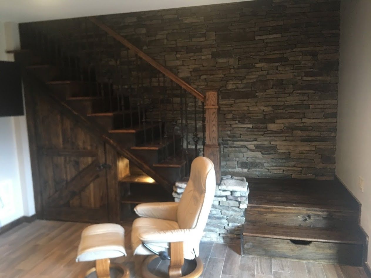 A living room with stairs and a chair and ottoman