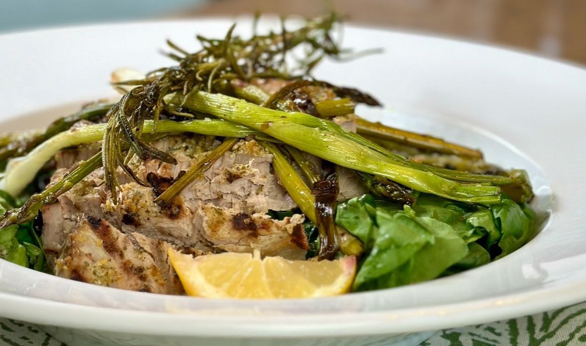 A close up of a plate of food with asparagus and meat on a table.