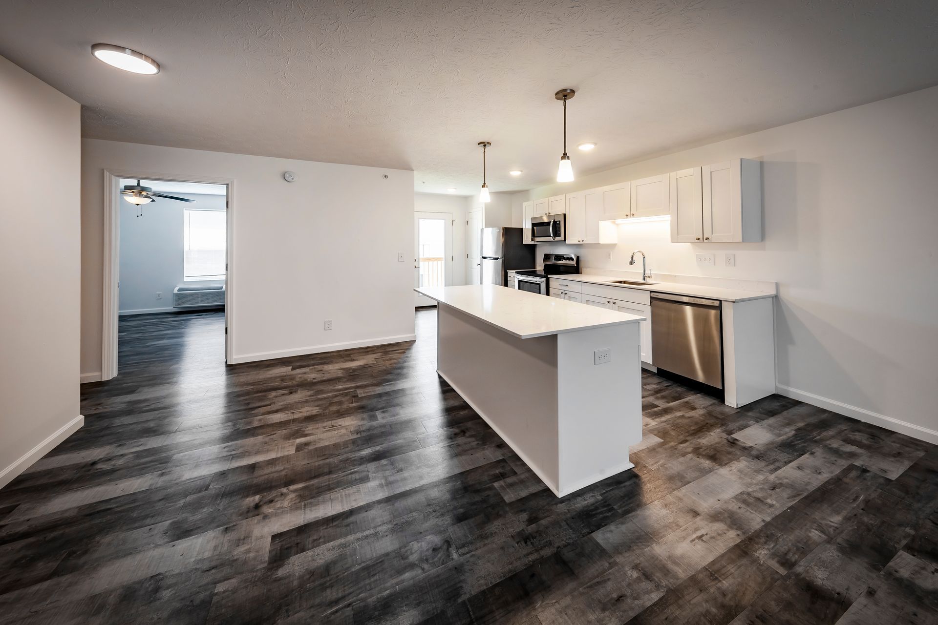 Bright modern kitchen featuring white shaker cabinets, a spacious center island, dark wood flooring, and an open-concept layout perfect for cooking, entertaining, and everyday living.