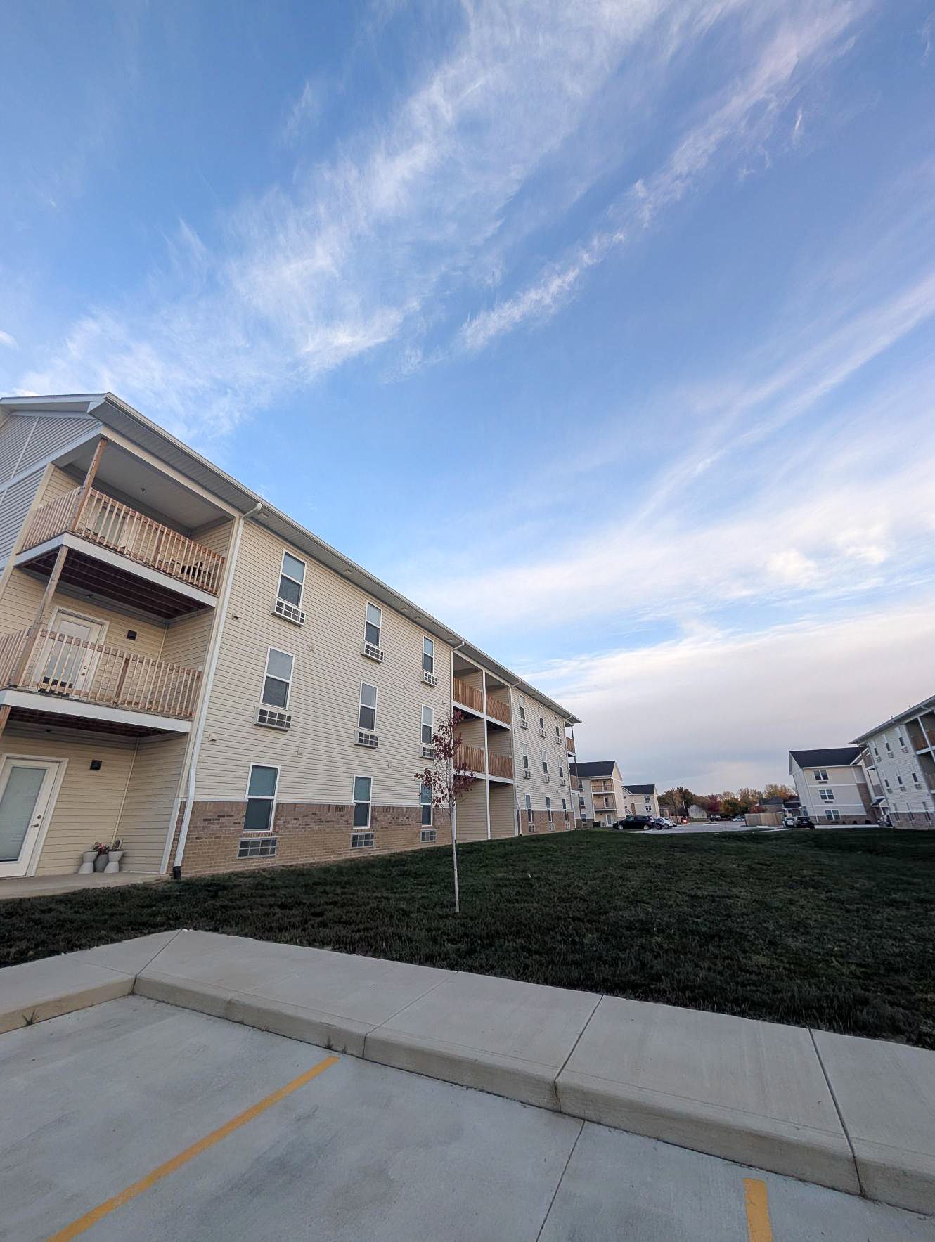 Reserve at Madison Flatts building with balconies and a grassy lawn under a blue sky.