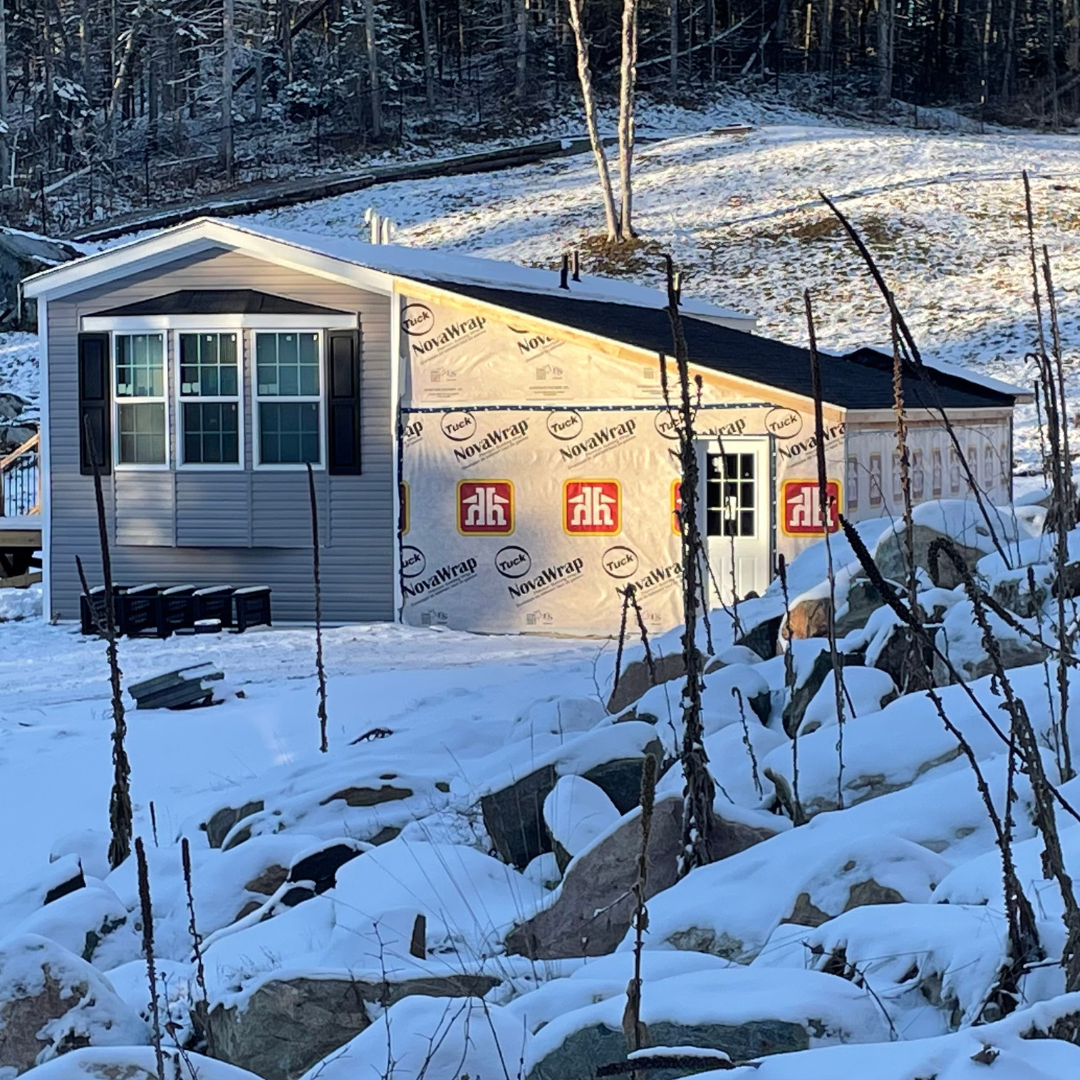 A small house is surrounded by snow and rocks.