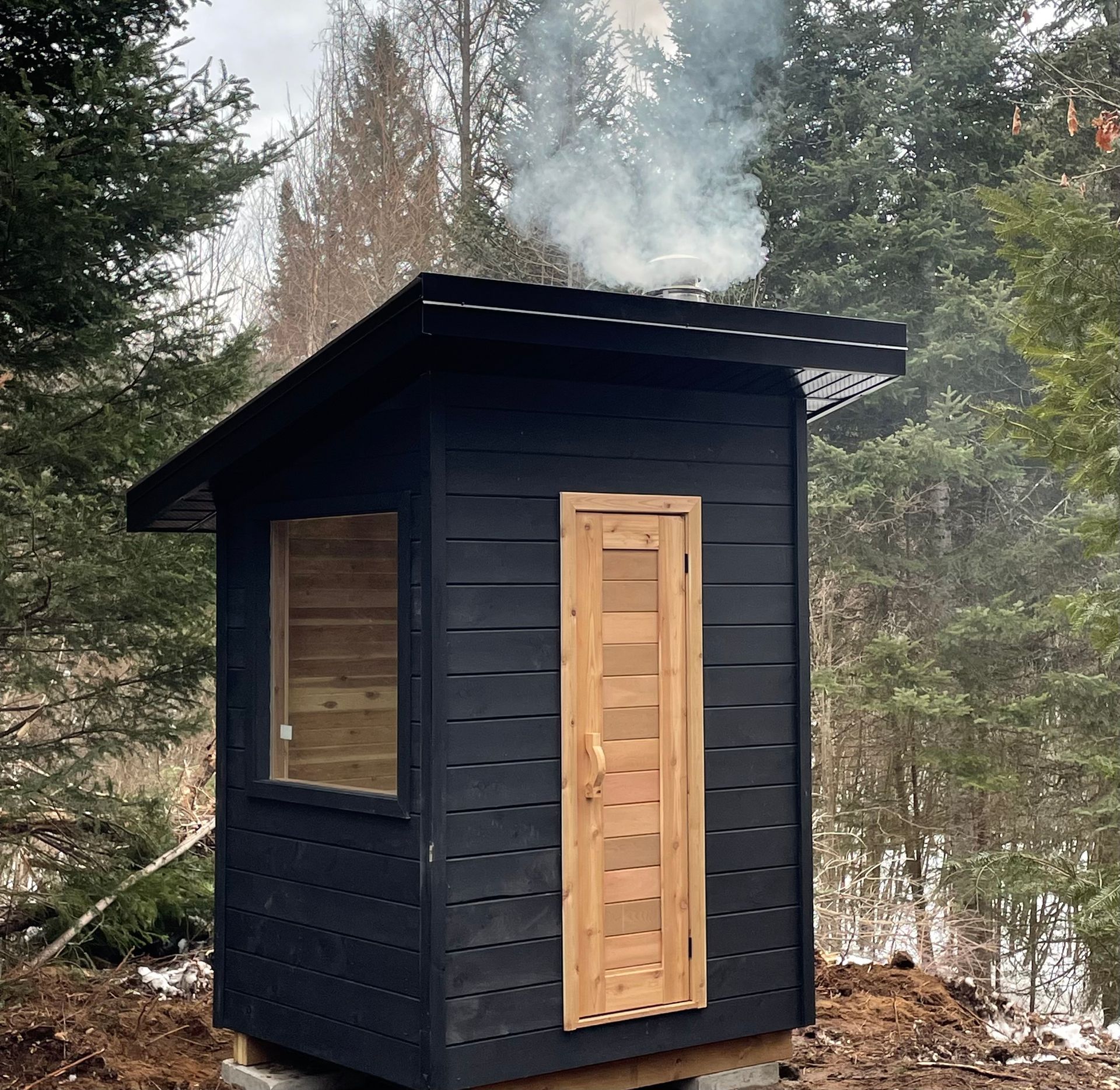 A small black shed with smoke coming out of the door
