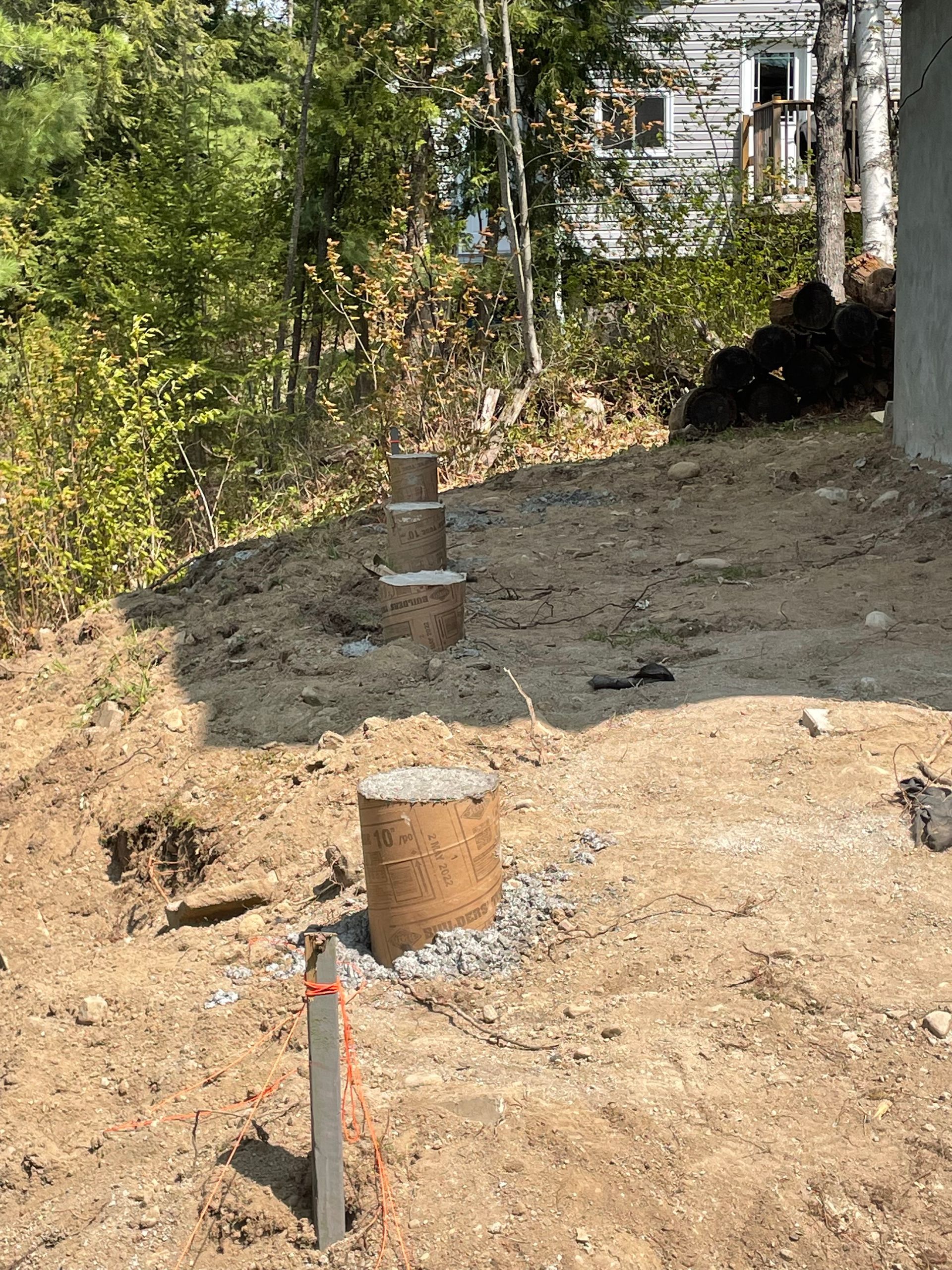 A pile of dirt is sitting on top of a dirt hill next to a house.