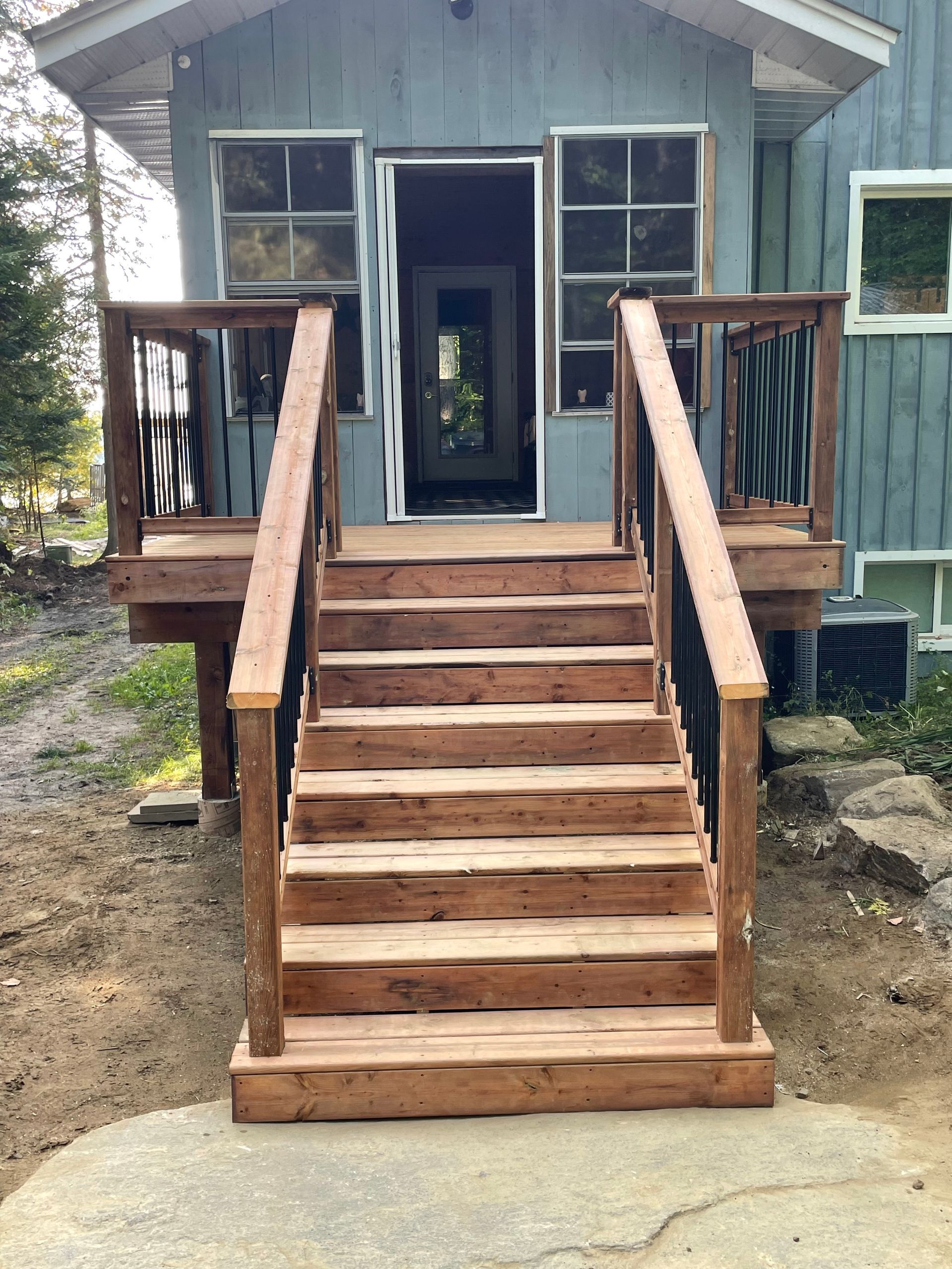 A wooden deck with stairs leading up to the front door of a house.