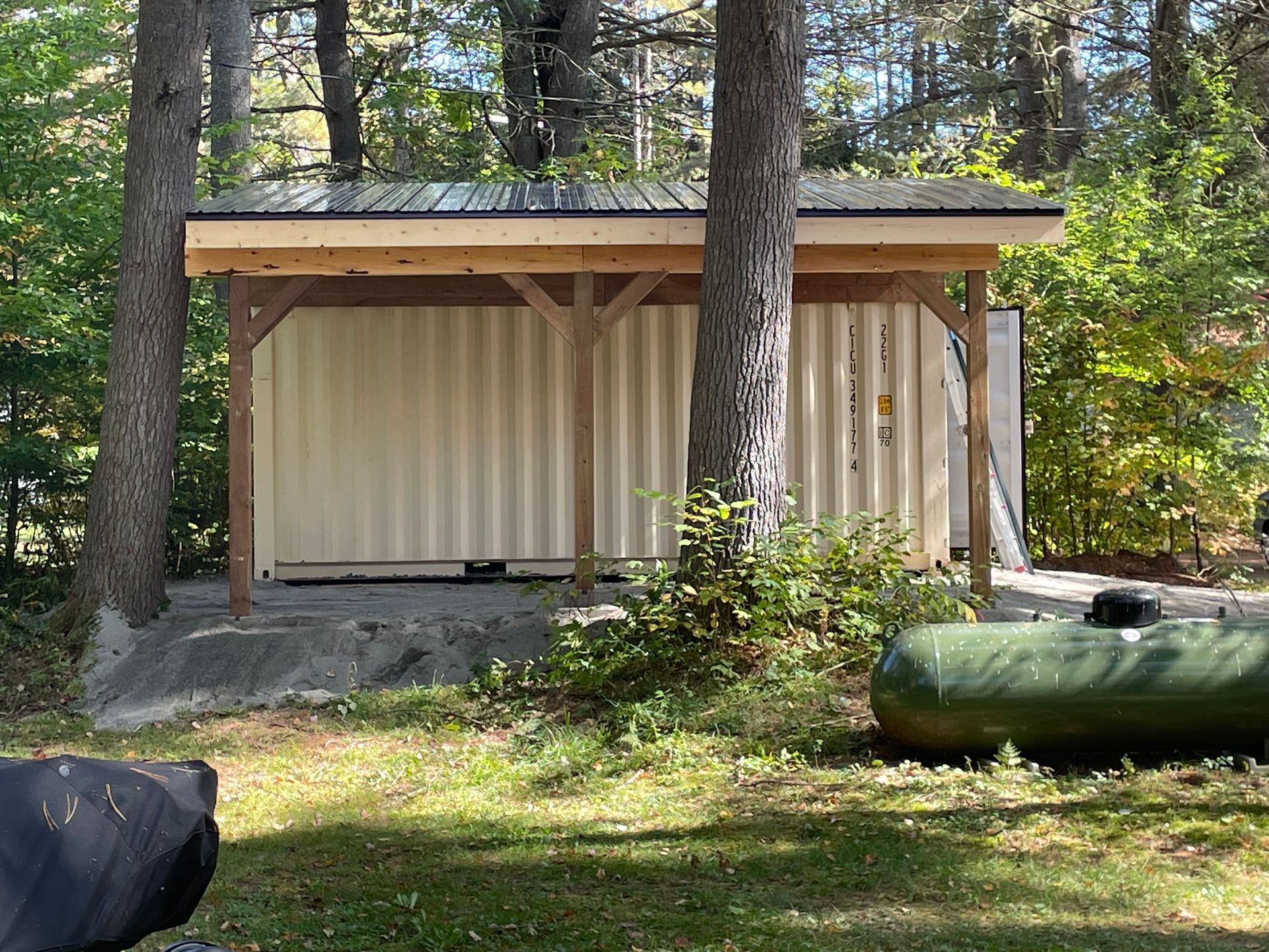 A shed is sitting in the middle of a lush green field surrounded by trees.