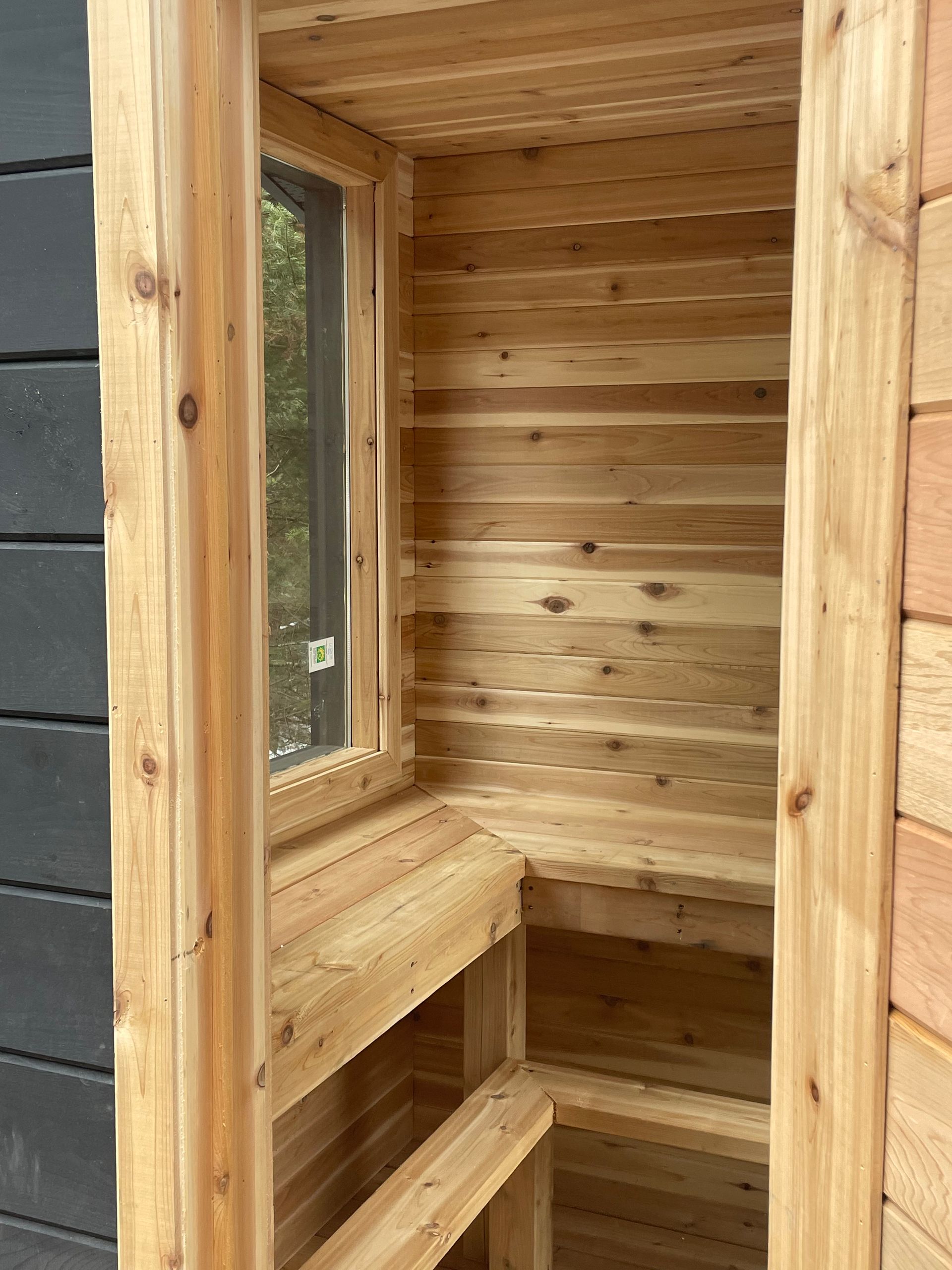 A wooden sauna with a window and a bench.