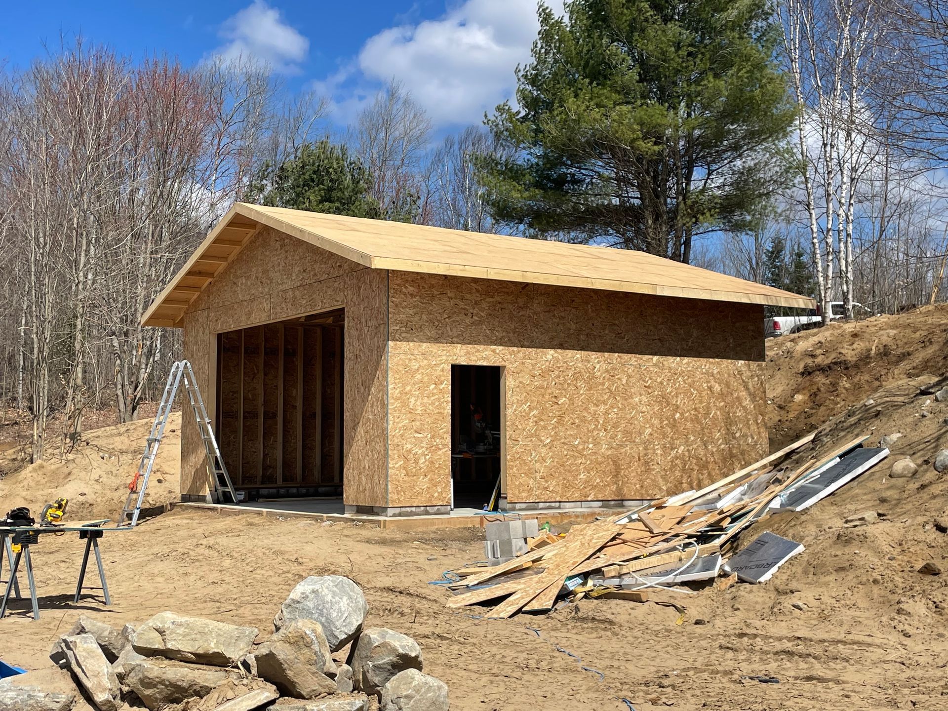 A wooden garage is being built in the middle of a dirt field.