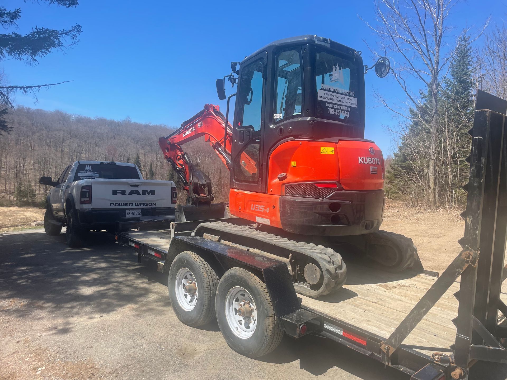 A truck is towing a small excavator on a trailer.