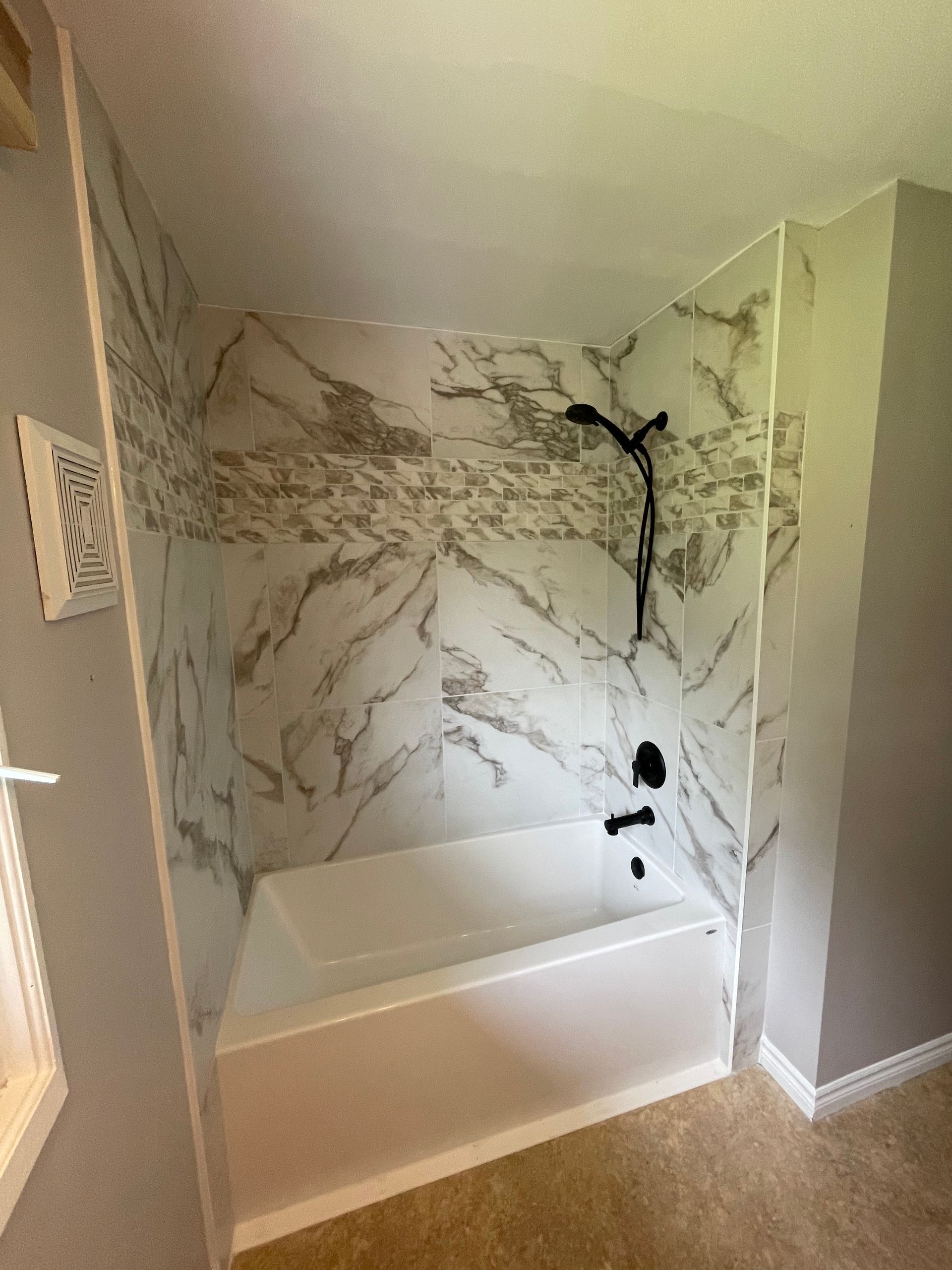 A bathroom with a bathtub and a shower stall with marble walls.
