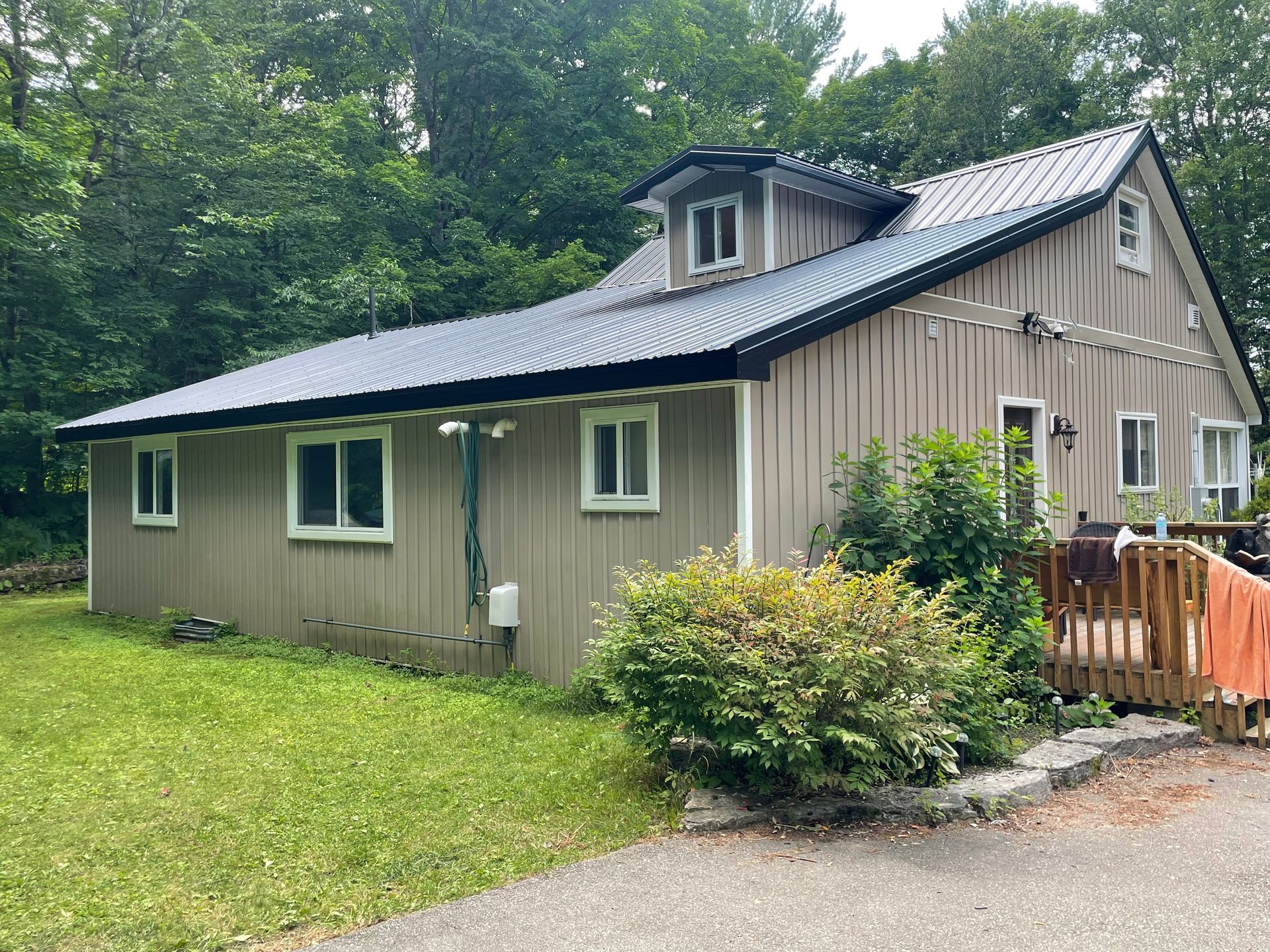 An aerial view of a green metal roof on a house in the woods.