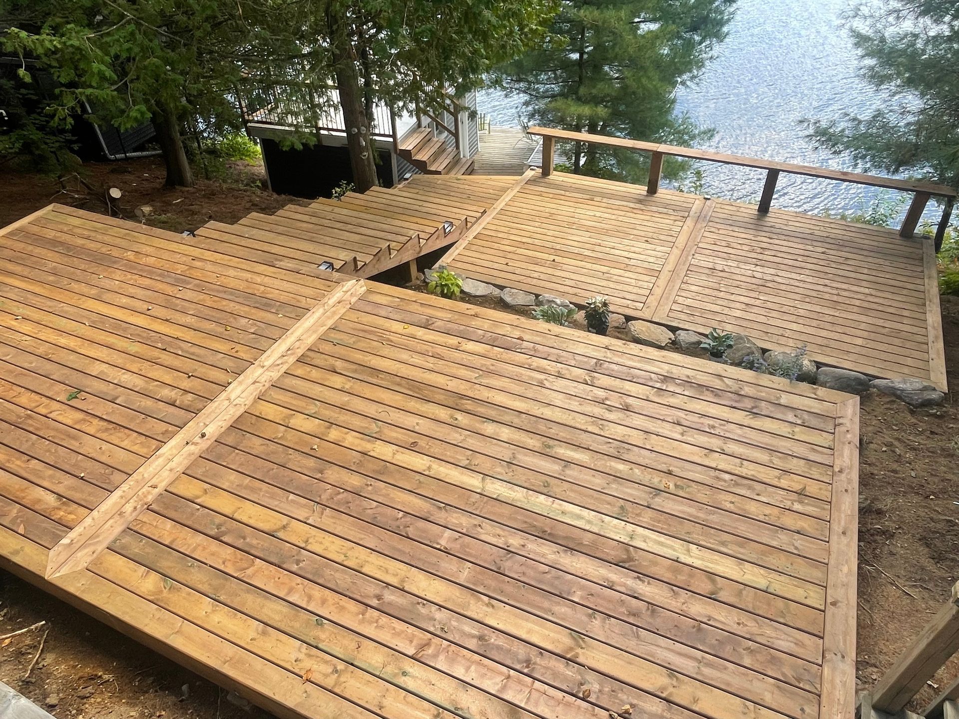 A wooden deck with stairs leading up to a lake.
