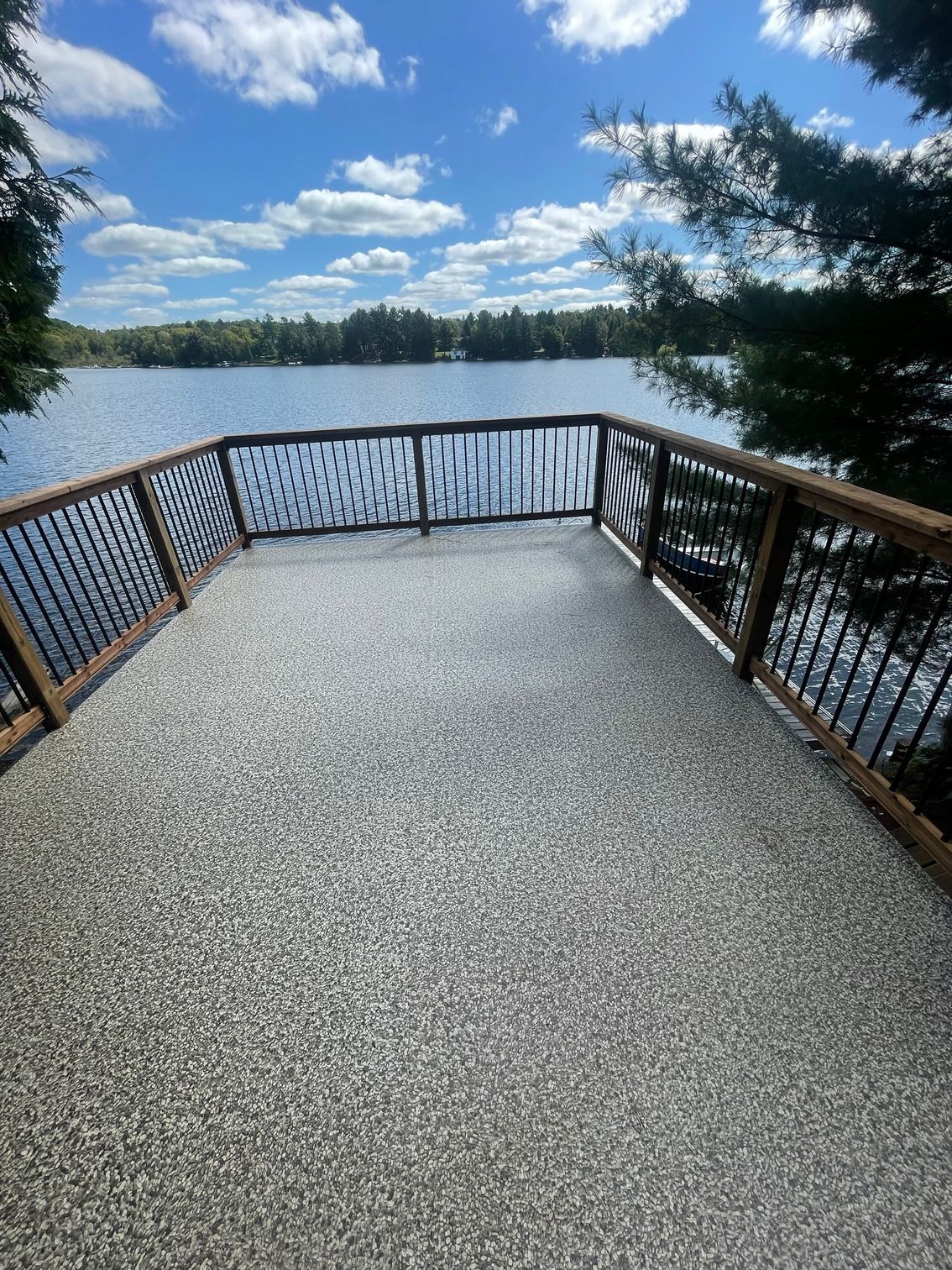 A large deck overlooking a lake with a wooden railing.