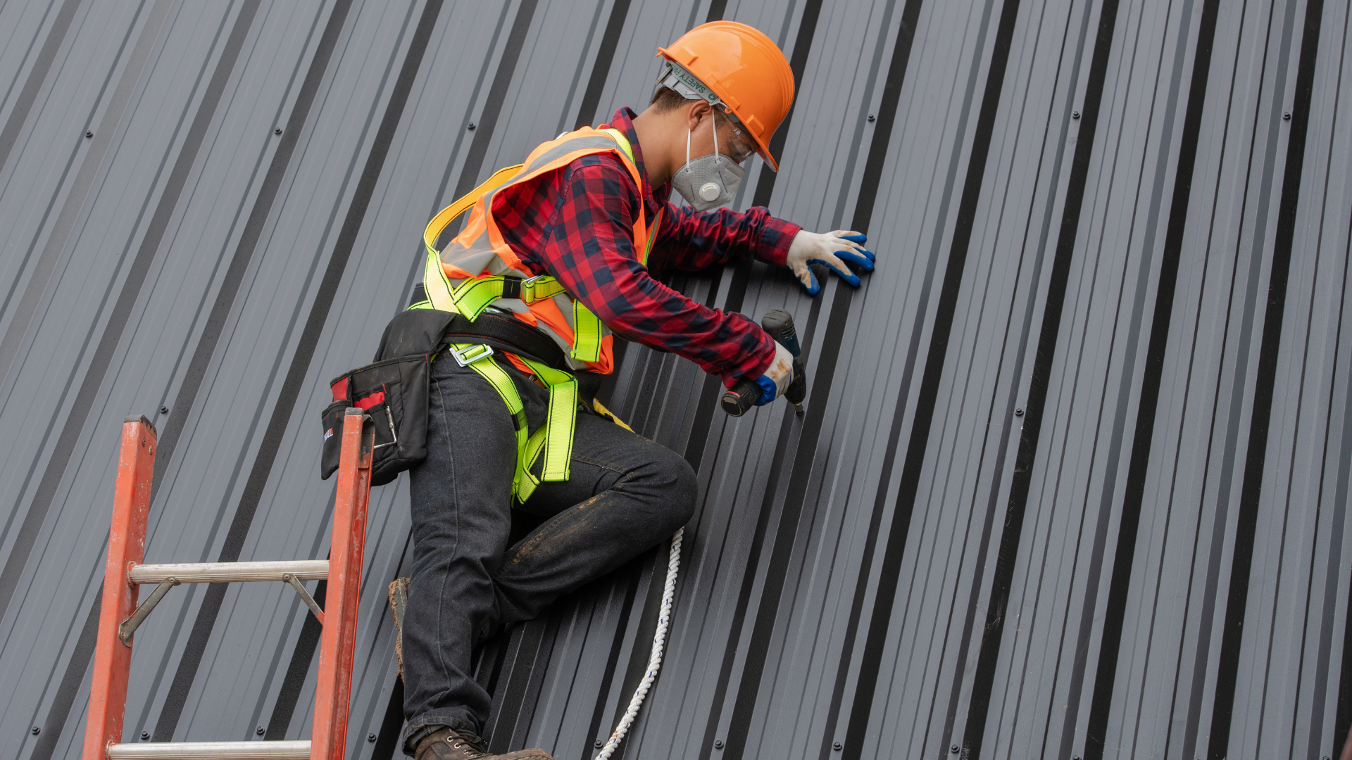 A man is sitting on a ladder working on a roof.