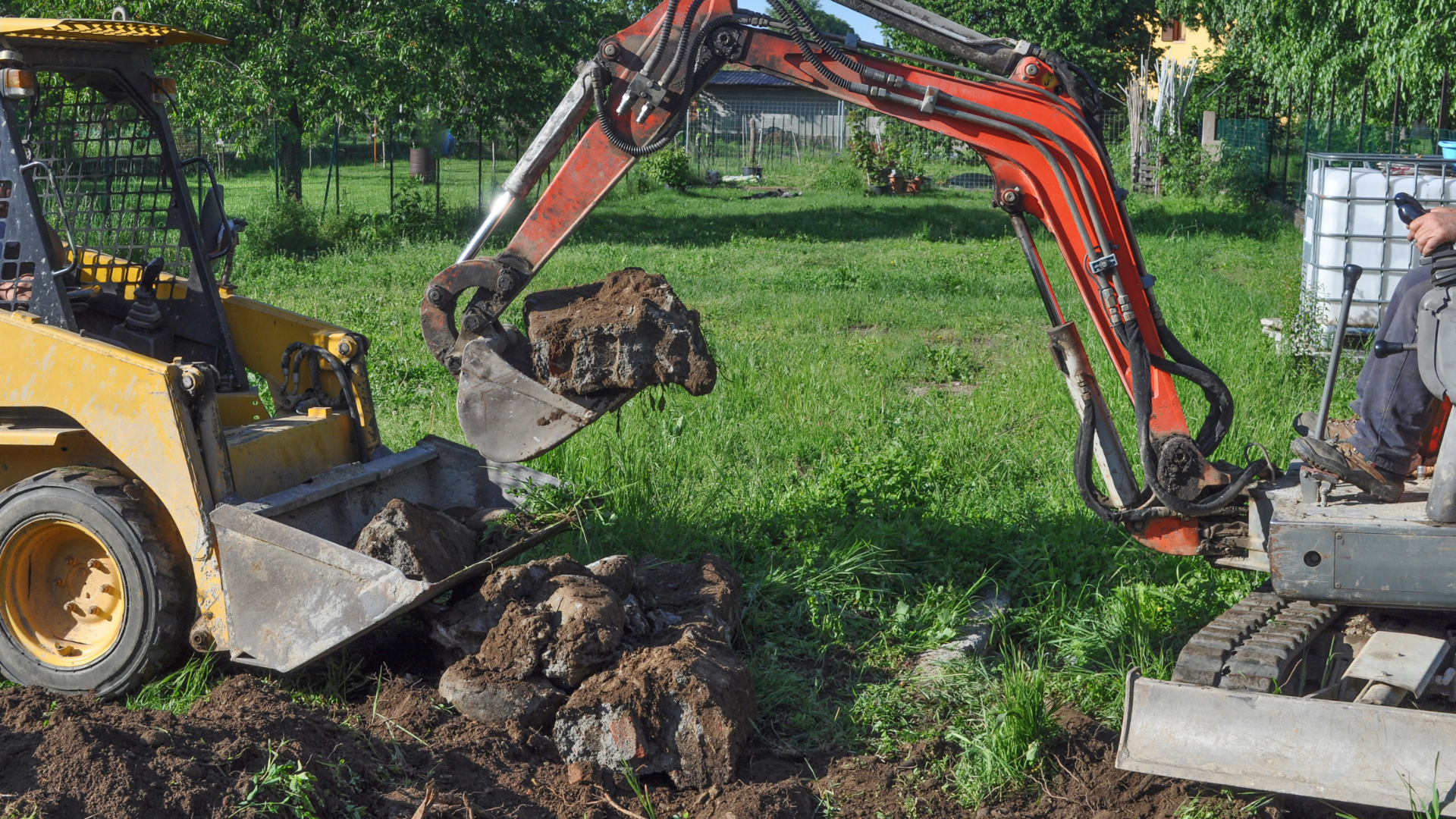 A man is driving a small excavator in a field.