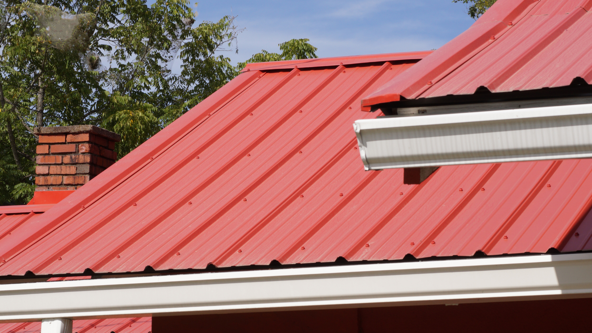 A red roof with a white gutter and a chimney