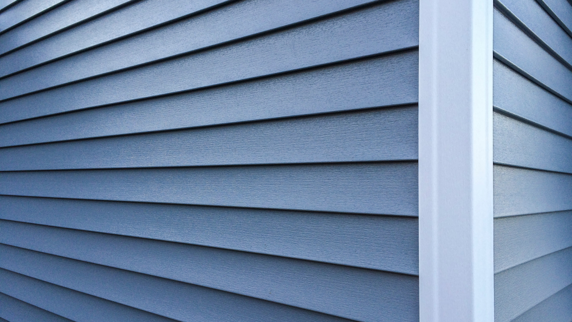 A close up of a blue siding on a house with a white trim.