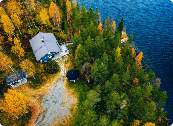 An aerial view of a house on the shore of a lake surrounded by trees.