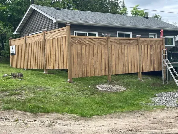 A wooden fence is in front of a house.
