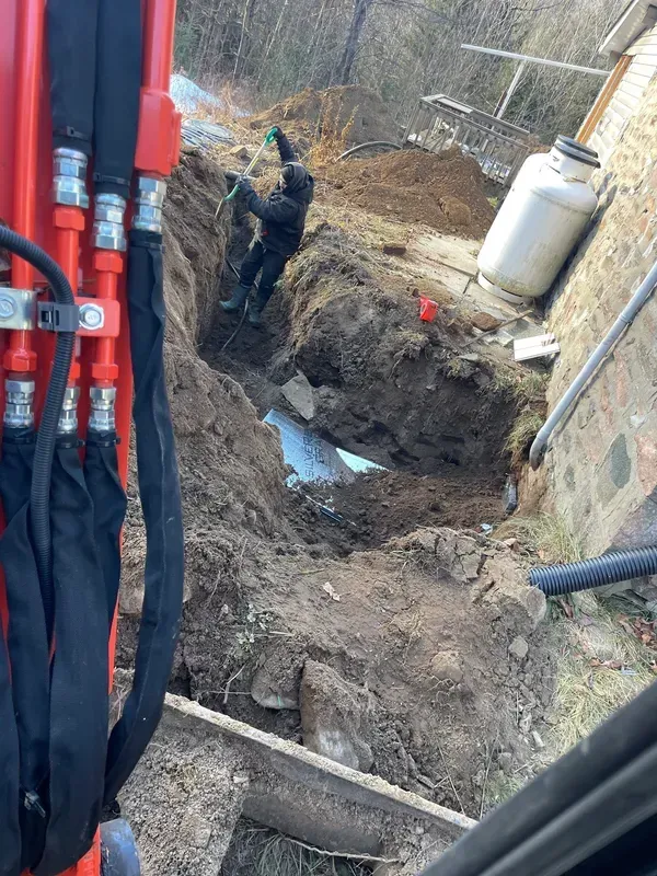 A man is digging a hole in the ground next to a building.