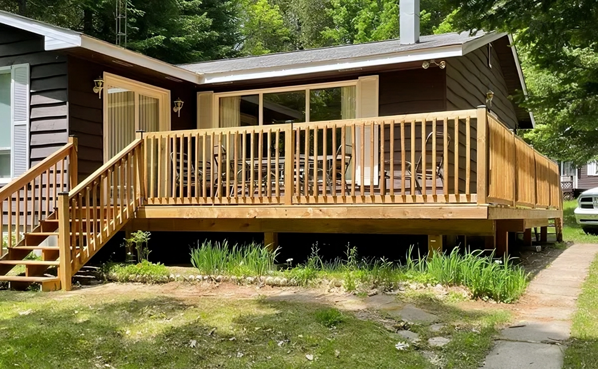 A small house with a large wooden deck and stairs.
