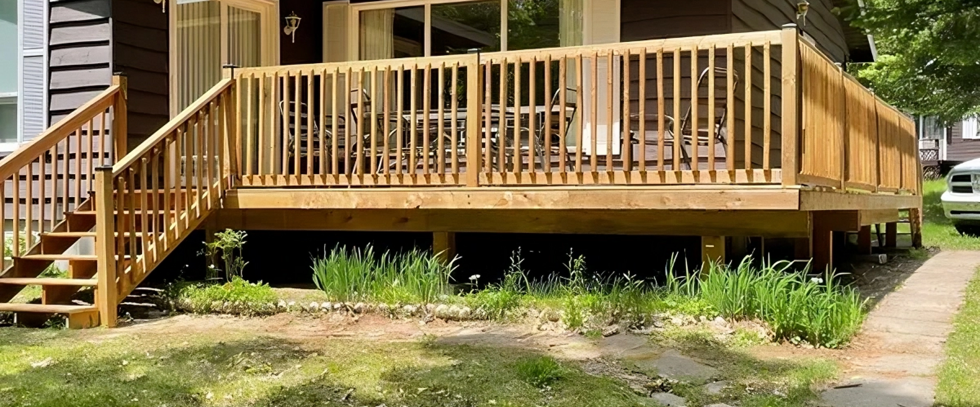 A wooden deck with stairs is in front of a house.