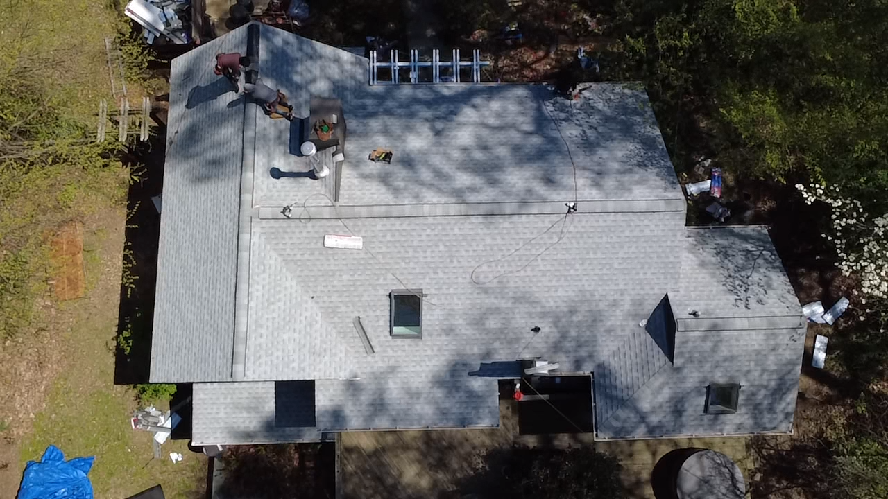 Overhead view of a house roof, various sections, damaged areas, materials, and a ladder.
