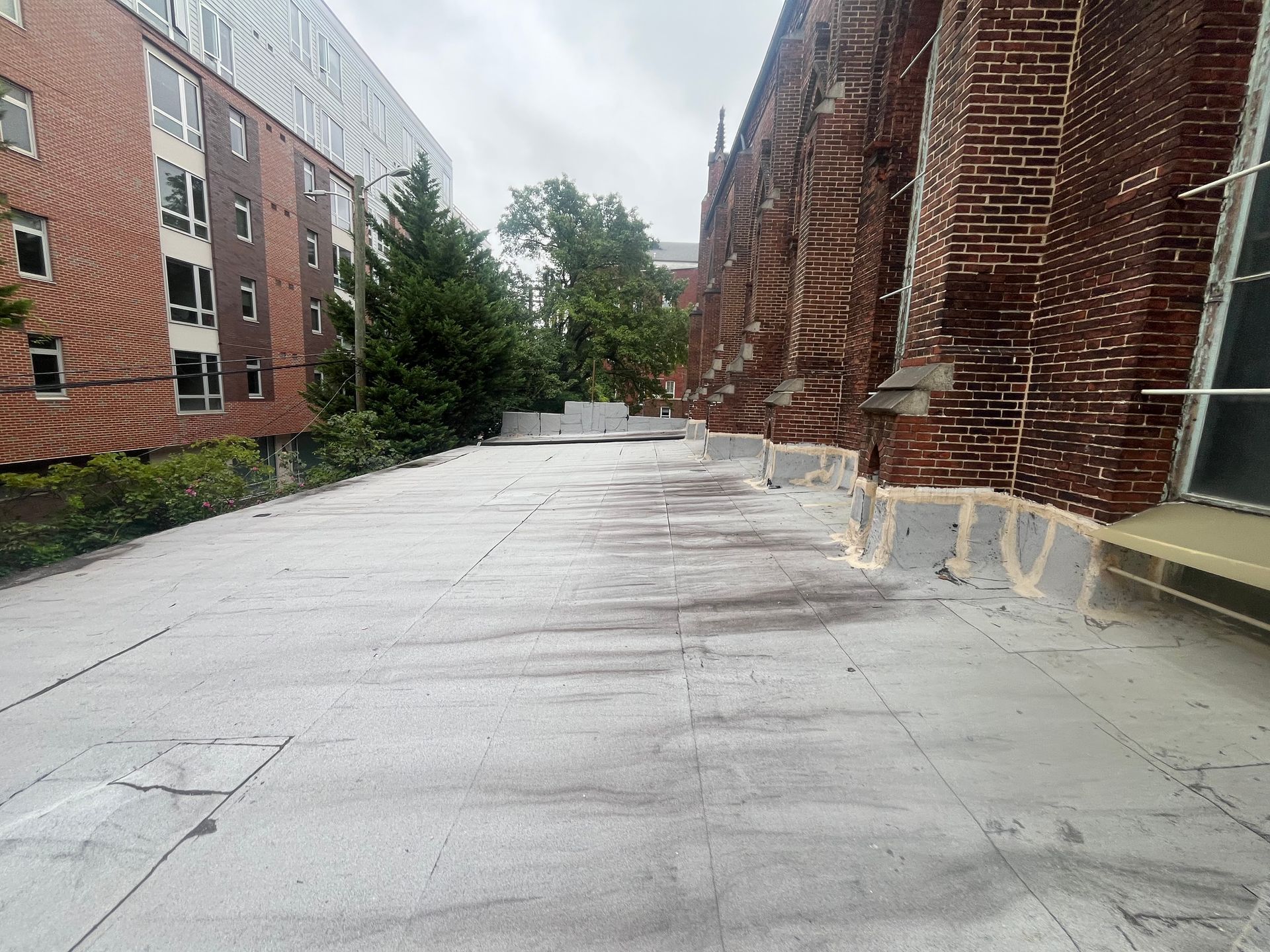 Flat rooftop with a brick building on the right and a modern building on the left.