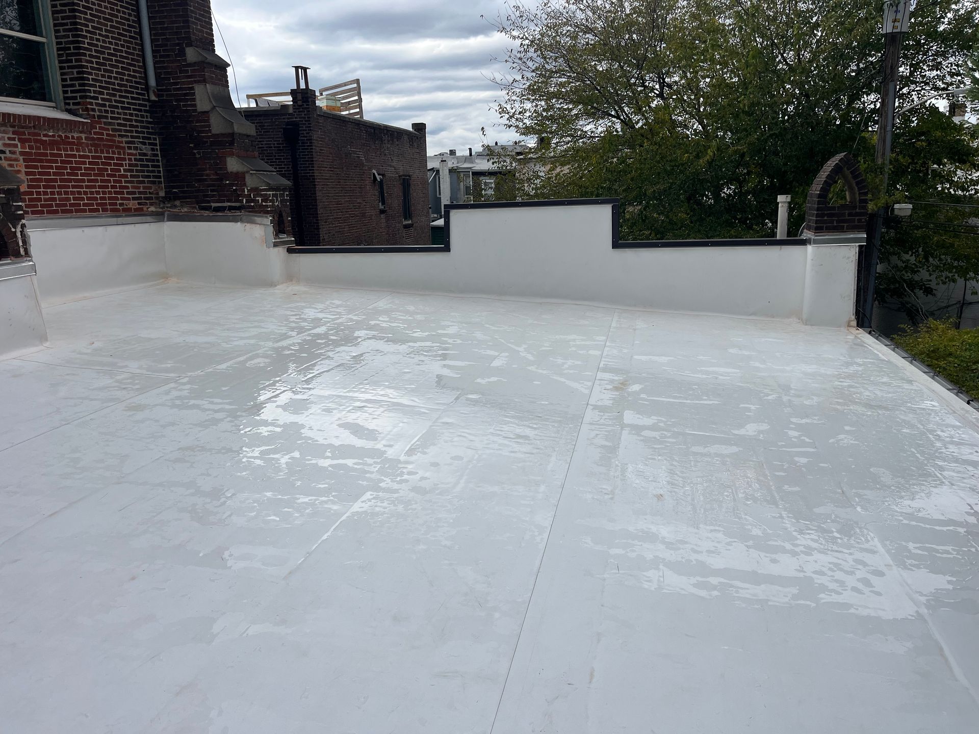 White roof with white walls and a brick building, cloudy sky background.