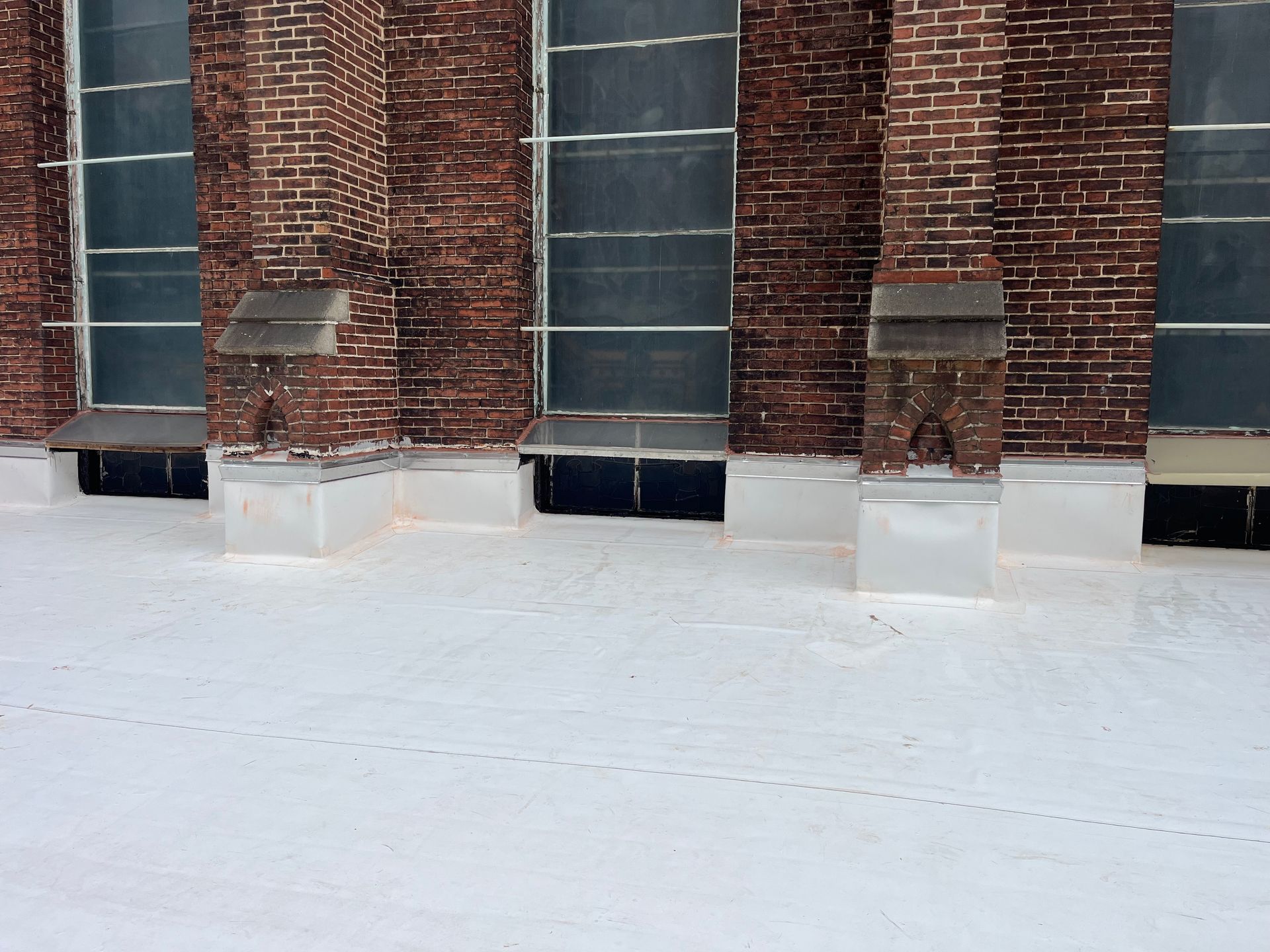 White roof with brick columns, metal vents, and windows.