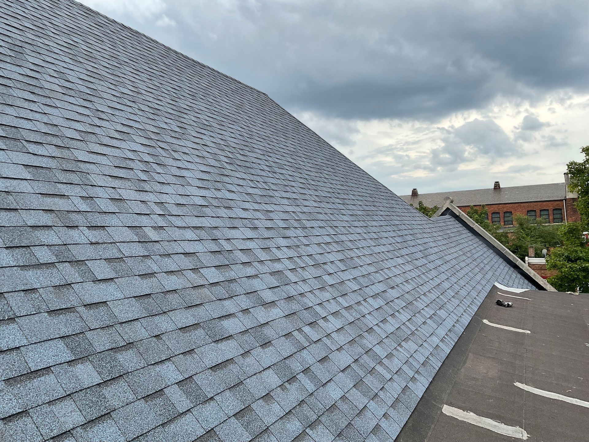 Gray asphalt shingle roof on a cloudy day, angled view.