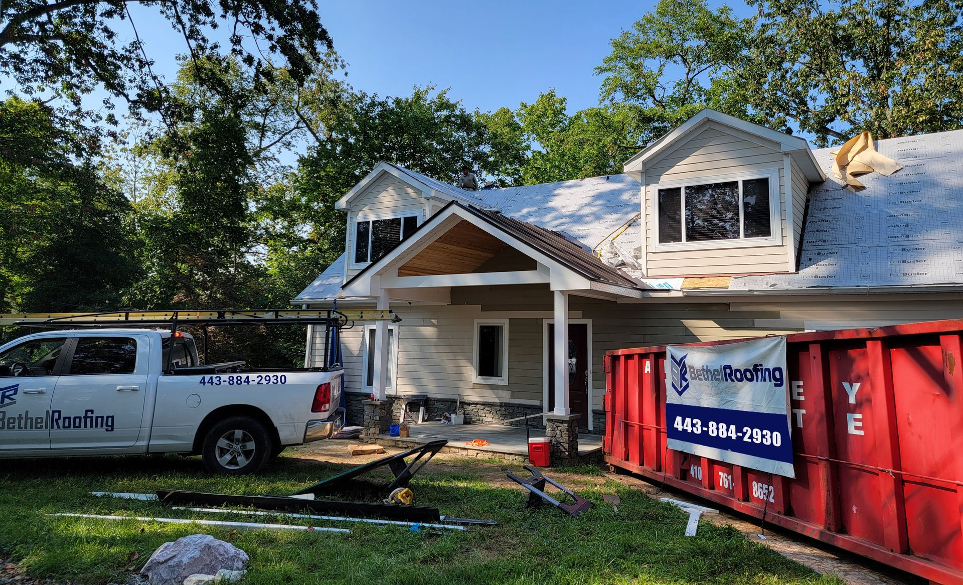 House under construction with a red dumpster and a white truck parked in front.