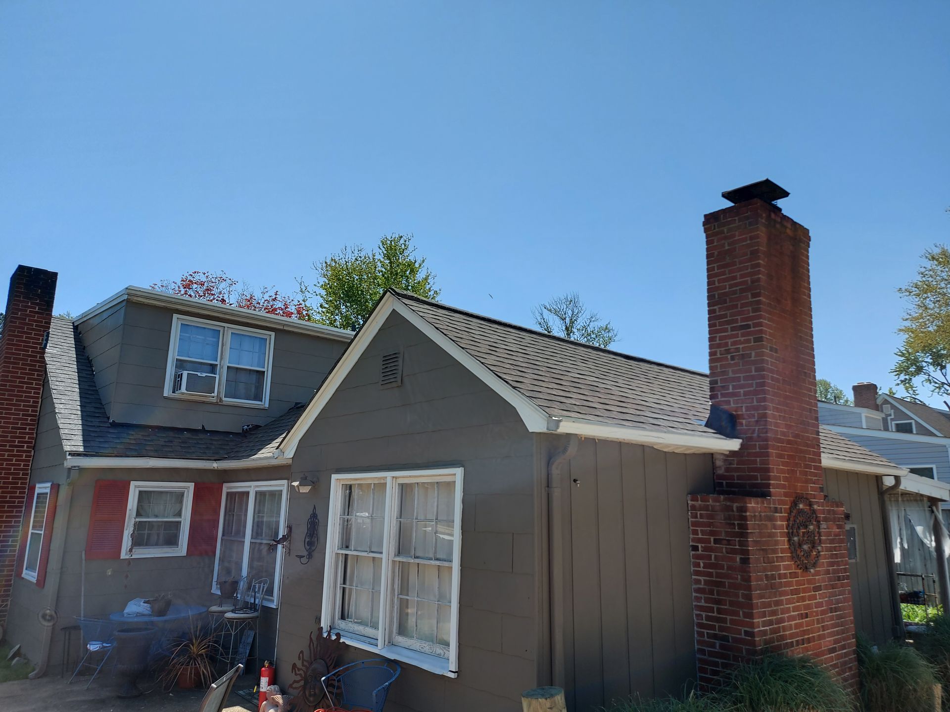 Gray house with two chimneys against a clear blue sky.