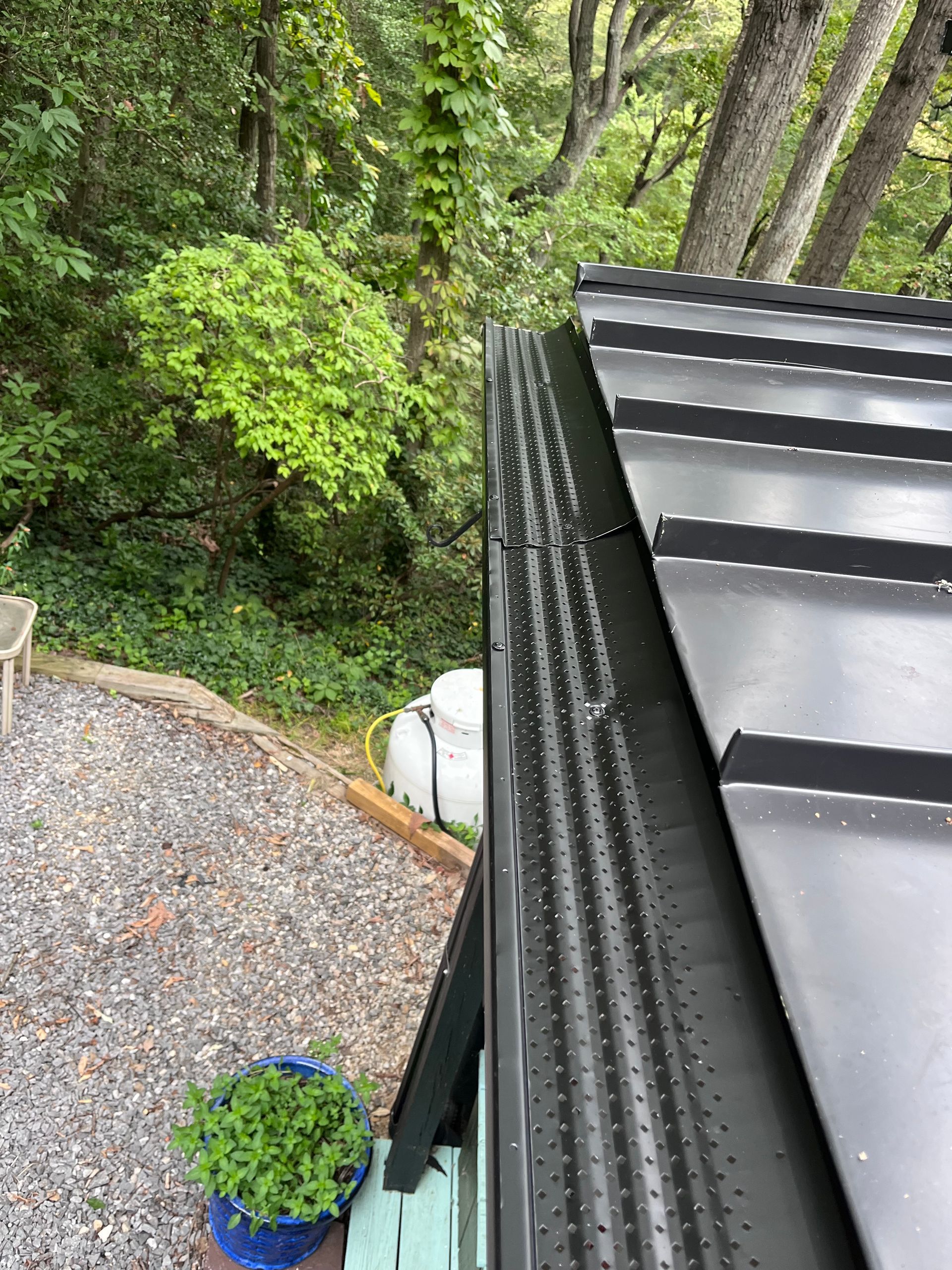 A white house with a black roof and a chain link fence