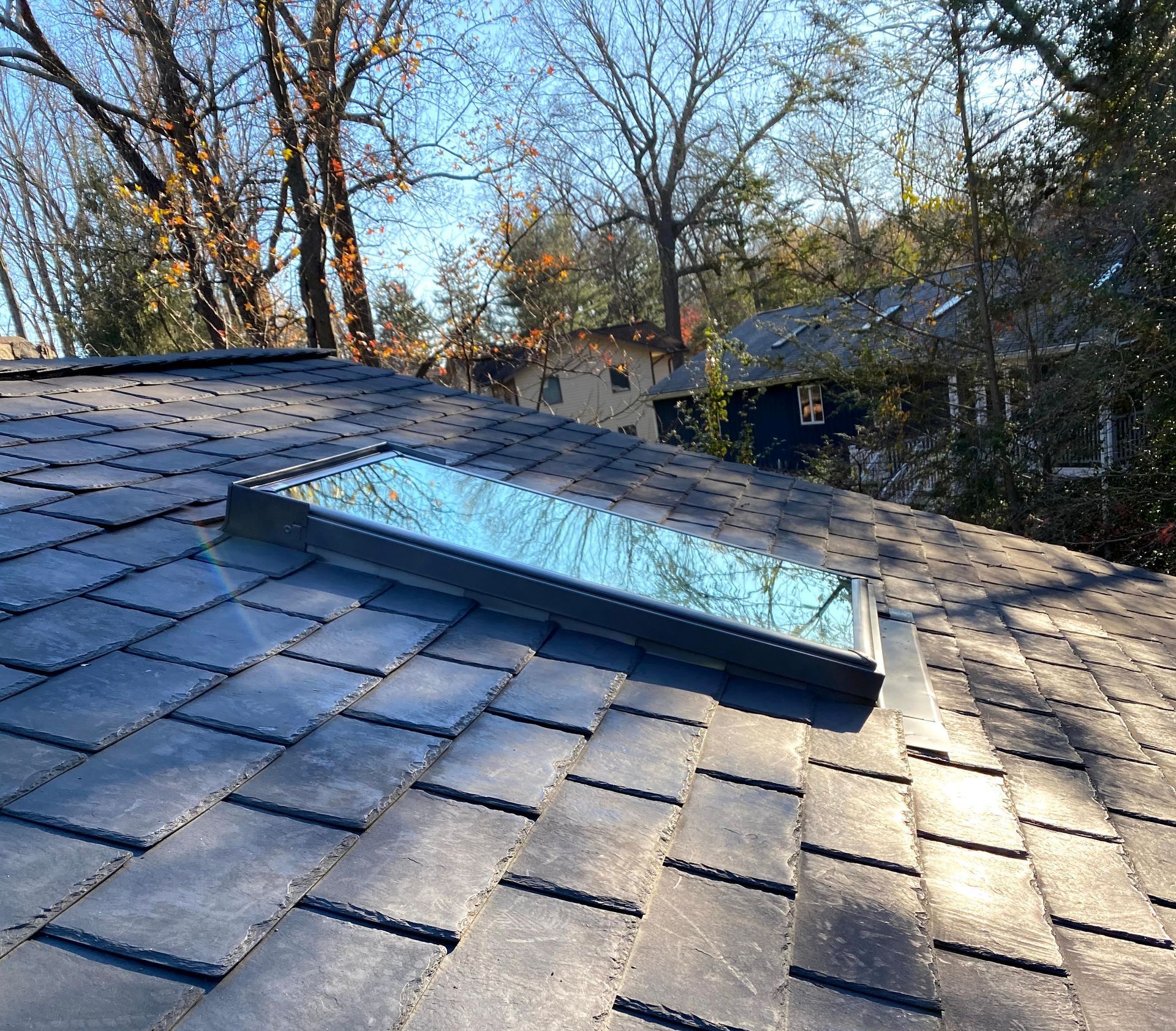A man is fixing a gutter on a house with a drill.