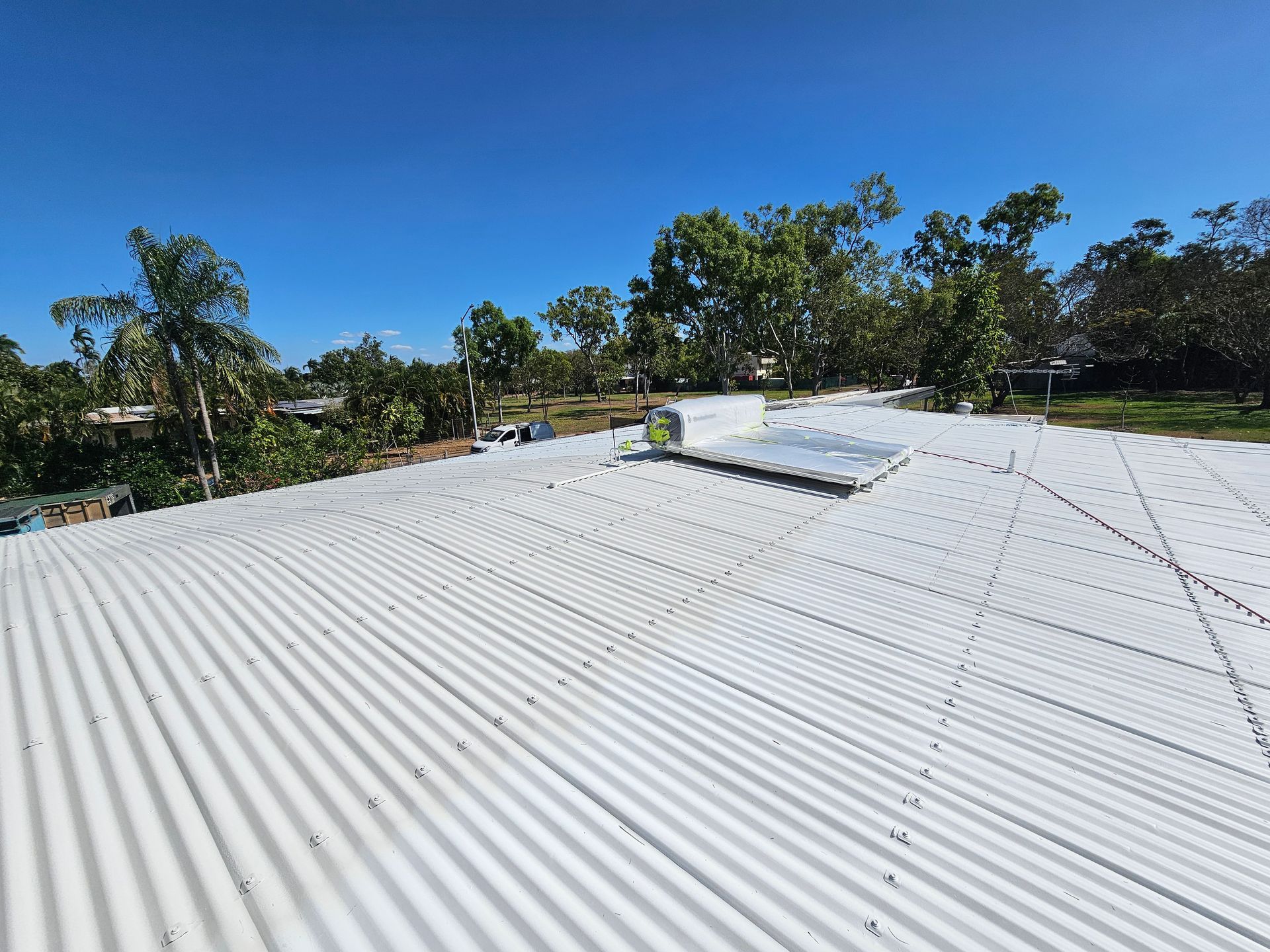 White Corrugated Metal Roof Under a Bright Blue Sky — Prestige Painting NT in Zuccoli, NT