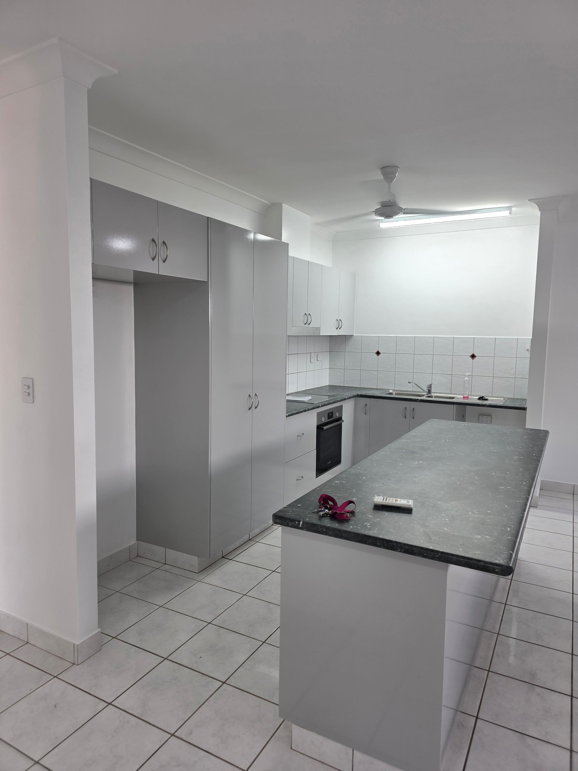 Kitchen with white cabinets, gray countertops, island, and tiled floor. — Prestige Painting NT in Zuccoli, NT