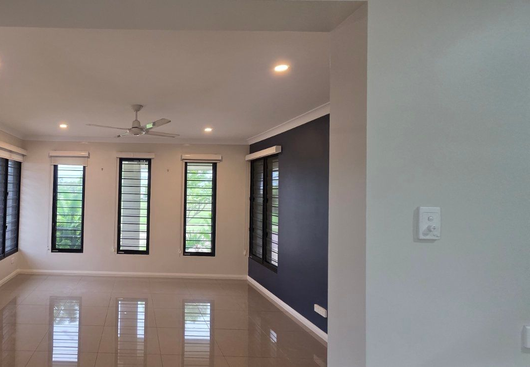 Empty living room with shiny tiled floor, windows, and dark blue accent wall. — Prestige Painting NT in Zuccoli, NT