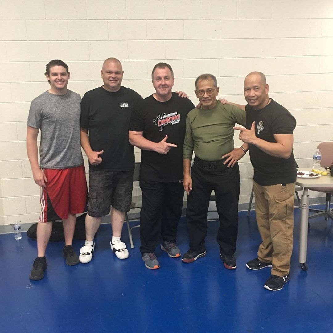 Two men grappling on a mat, one in blue, the other in black.