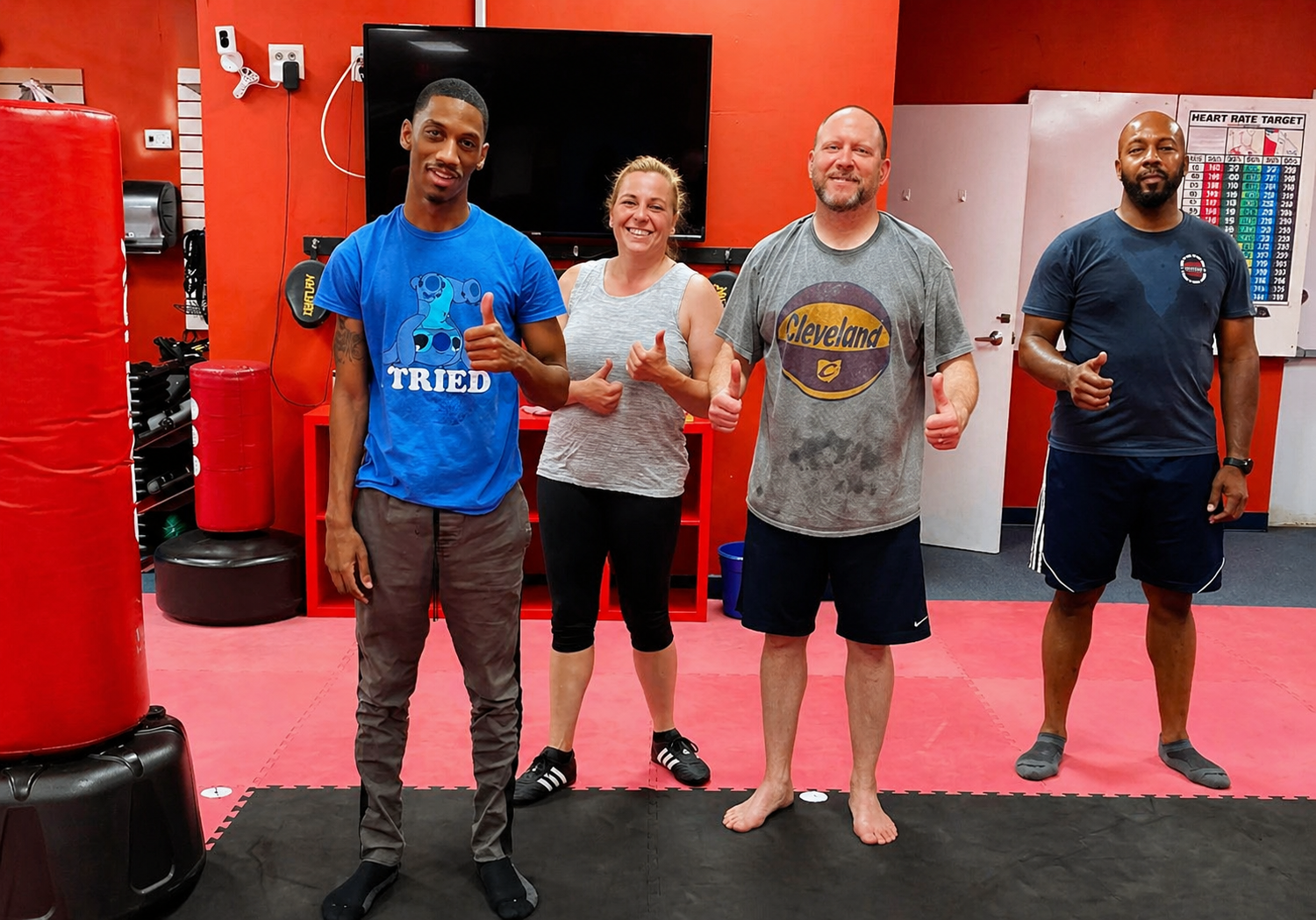 People practicing jiu-jitsu on mats, wearing gis in blue, black, and gray. Active grappling, gym setting.