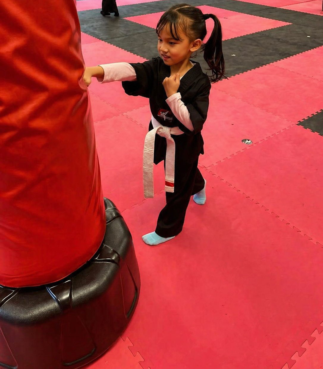 Two boys on a mat practicing Jiu-Jitsu. One boy is on top, giving a thumbs-up.