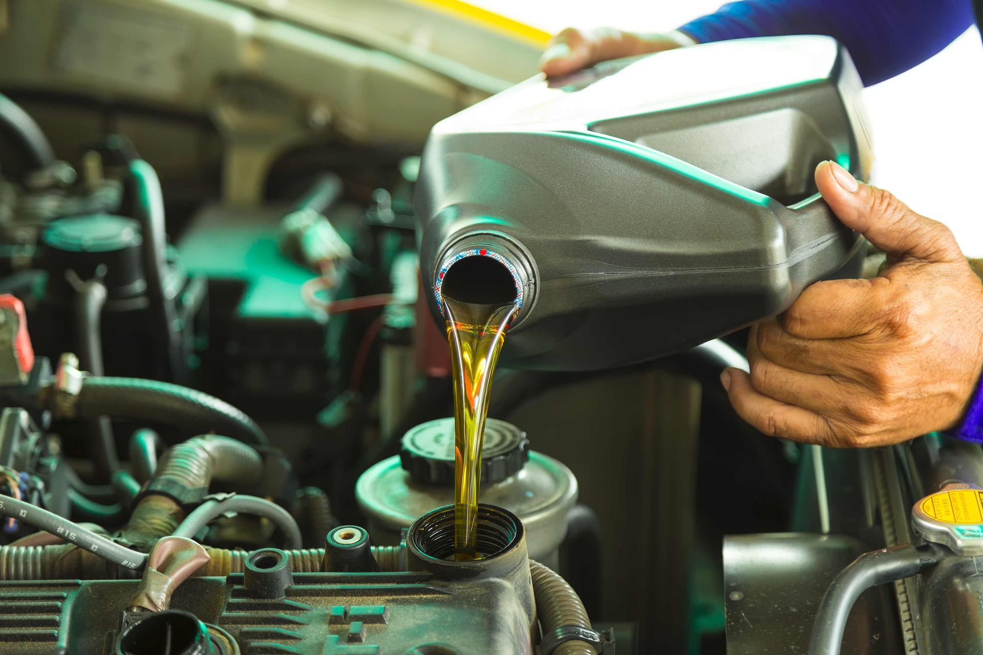 a person is pouring oil into a car engine